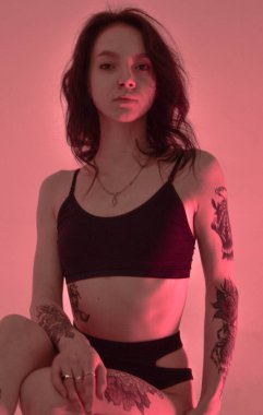 Erotik kız iç çamaşırlarıyla yerde ve pembeyle oturuyor.