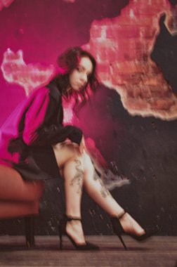 Ceketli bir kız ve kırmızı neonlu seksi ayakkabılar.