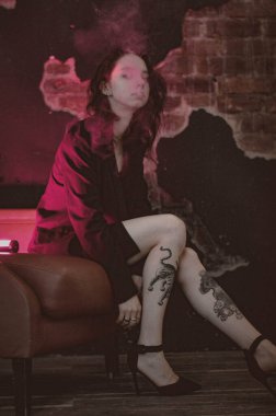 Ceketli ve seksi bir kız kırmızı neonlu sigara içiyor.