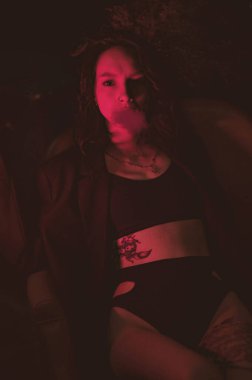 Ceketli ve seksi bir kız kırmızı neonlu sigara içiyor.