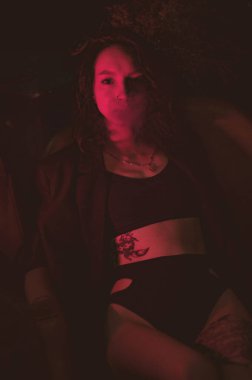 Ceketli ve seksi bir kız kırmızı neonlu sigara içiyor.