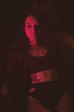 Ceketli ve seksi bir kız kırmızı neonlu sigara içiyor.