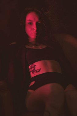 Ceketli ve seksi bir kız kırmızı neonlu sigara içiyor.