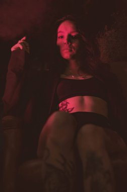 Ceketli bir kız ve kırmızı neonlu seksi ayakkabılar.