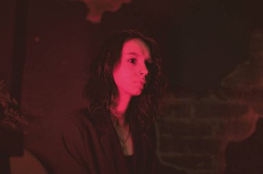 Ceketli ve seksi bir kız kırmızı neonlu sigara içiyor.