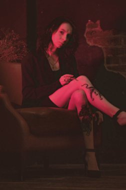 Ceketli ve seksi bir kız kırmızı neonlu sigara içiyor.