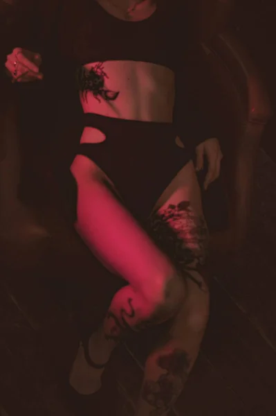 Ceketli ve seksi bir kız kırmızı neonlu bir koltukta yatıyor.