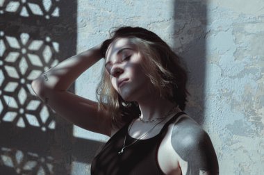 Güneşli bir odada siyah saçlı ve şortlu bir kız.