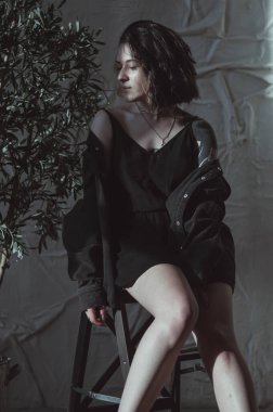 Güneşli bir odada siyah saçlı ve şortlu bir kız.