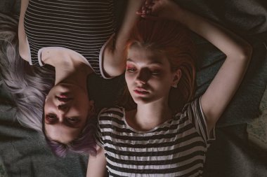 Çizgili tişörtlü ikizler halının üzerinde yatıyor.