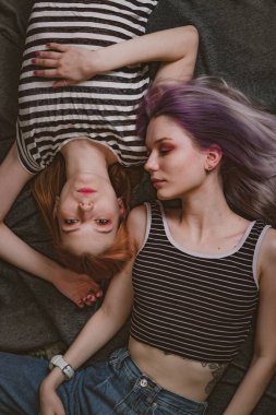 Çizgili tişörtlü ikizler halının üzerinde yatıyor.