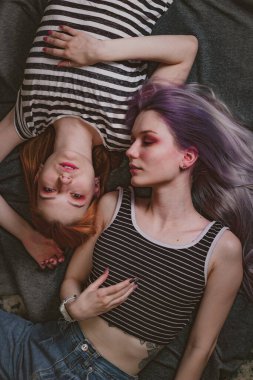 Çizgili tişörtlü ikizler halının üzerinde yatıyor.