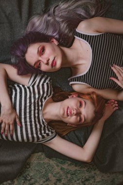 Çizgili tişörtlü ikizler halının üzerinde yatıyor.