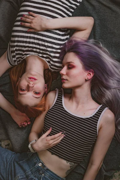 Çizgili tişörtlü ikizler halının üzerinde yatıyor.