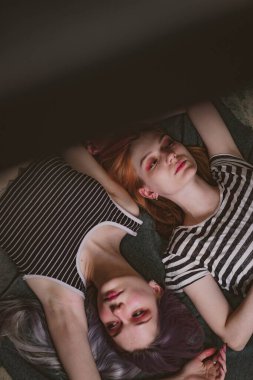 Çizgili tişörtlü ikizler halının üzerinde yatıyor.