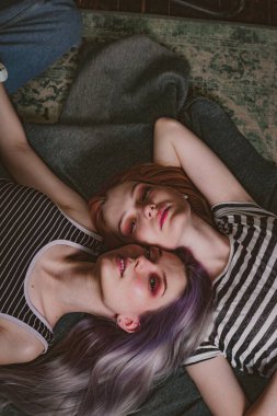 Çizgili tişörtlü ikizler halının üzerinde yatıyor.