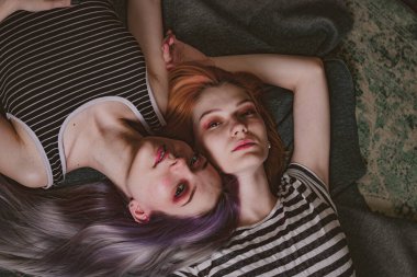 Çizgili tişörtlü ikizler halının üzerinde yatıyor.