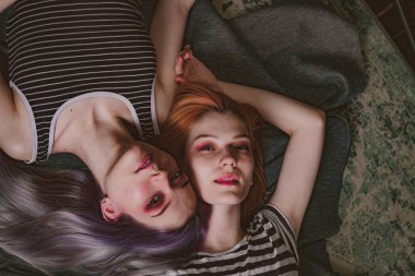 Çizgili tişörtlü ikizler halının üzerinde yatıyor.