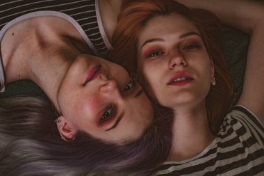 Çizgili tişörtlü ikizler halının üzerinde yatıyor.