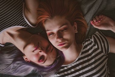 Çizgili tişörtlü ikizler halının üzerinde yatıyor.