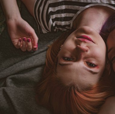 Çizgili tişörtlü ikizler halının üzerinde yatıyor.