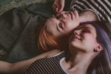 Çizgili tişörtlü ikizler halının üzerinde yatıyor.