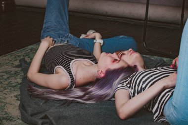 Çizgili tişörtlü ikizler halının üzerinde yatıyor.