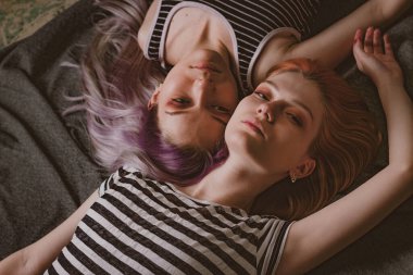 Çizgili tişörtlü ikizler halının üzerinde yatıyor.