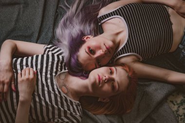 Çizgili tişörtlü ikizler halının üzerinde yatıyor.