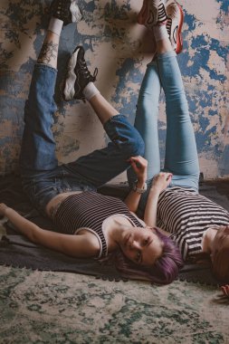 Çizgili tişörtlü ikizler halının üzerinde yatıyor.