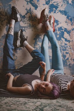 Çizgili tişörtlü ikizler halının üzerinde yatıyor.