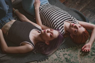 Çizgili tişörtlü ikizler halının üzerinde yatıyor.