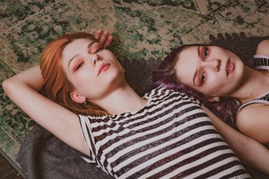 Çizgili tişörtlü ikizler halının üzerinde yatıyor.