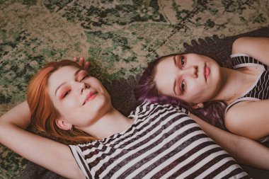 Çizgili tişörtlü ikizler halının üzerinde yatıyor.