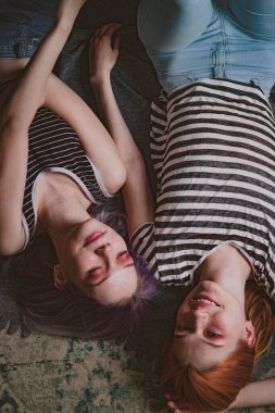 Çizgili tişörtlü ikizler halının üzerinde yatıyor.