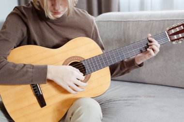 Yakışıklı genç adam akustik enstrümantal gitar çalıyor.