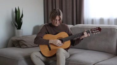 Yakışıklı genç adam akustik enstrümantal gitar çalıyor.