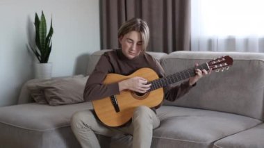 Yakışıklı genç adam akustik enstrümantal gitar çalıyor.