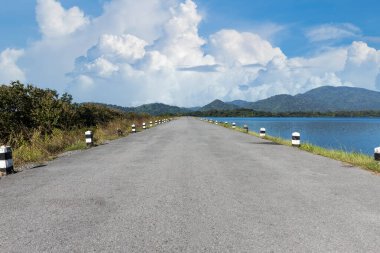 Boş bir yolda araba kullanmak. Yeşil tarlalarda boş asfalt yol ve yaz günü mavi gökyüzünde bulutlar. Önümüzde açık yol, konsept için sonsuz yol.