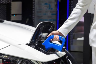 Elektrikli araba şarj aleti. Elektrikli Araç EV şarj istasyonu ve şarj aleti. İnsan eli, elektrikli araba şarjına bağlı..