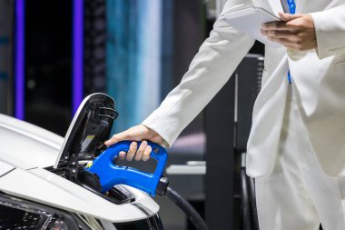 Elektrikli araba şarj aleti. Elektrikli Araç EV şarj istasyonu ve şarj aleti. İnsan eli, elektrikli araba şarjına bağlı..