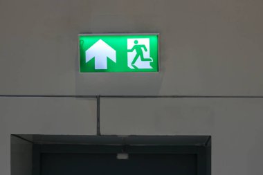 Kaçış yolunu gösteren yeşil acil çıkış işareti. Binadaki yangın çıkışı..