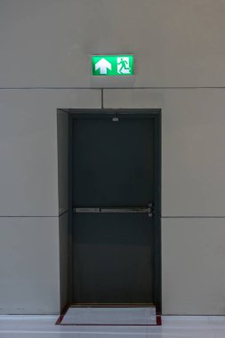 Kaçış yolunu gösteren yeşil acil çıkış işareti. Binadaki yangın çıkışı..