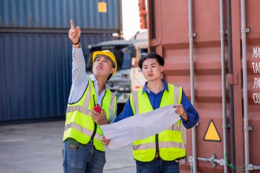 Konteyner kargo alanında çalışan profesyonel ustabaşı konteynırdaki malları kontrol ediyor. İşçiler denetleme ve kontrol için konteynırları açıyorlar..