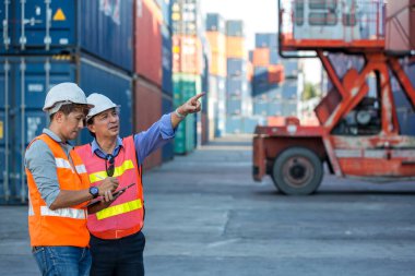 Ustabaşı konteyner kargo limanında konteynırları yüklemeye çalışıyor. Konteyner kargo alanında çalışan profesyonel ustabaşı konteynırdaki malları kontrol ediyor. İşçiler konteynırları kontrol için açıyorlar.