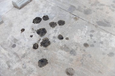 Beton zeminde motor yağı sızıntısı var. Beton zeminde siyah motor yağı. Motordan motor yağı sızıyor. Motor yağı lekeli yüzey betonu gri siyah gümüş..