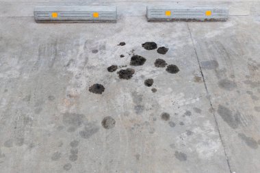 Beton zeminde motor yağı sızıntısı var. Beton zeminde siyah motor yağı. Motordan motor yağı sızıyor. Motor yağı lekeli yüzey betonu gri siyah gümüş..