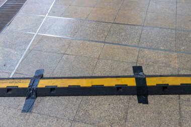 Kablo koruyucu örtü. Elektrik kablosu için koruma. Parkın kaldırımındaki elektrik kablolarını korumak için kaldırım altlıkları. Yoldaki kabloların üzerinden geçmeleri için ağır plastik örtüler.. 