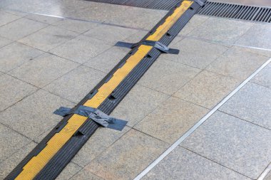 Kablo koruyucu örtü. Elektrik kablosu için koruma. Parkın kaldırımındaki elektrik kablolarını korumak için kaldırım altlıkları. Yoldaki kabloların üzerinden geçmeleri için ağır plastik örtüler.. 