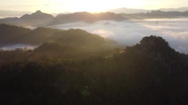 Beyaz sis ya da bulutlu manzaralı hava manzarası. Bulutlar arasında uçuyor ve dağın tepelerinde sis var..